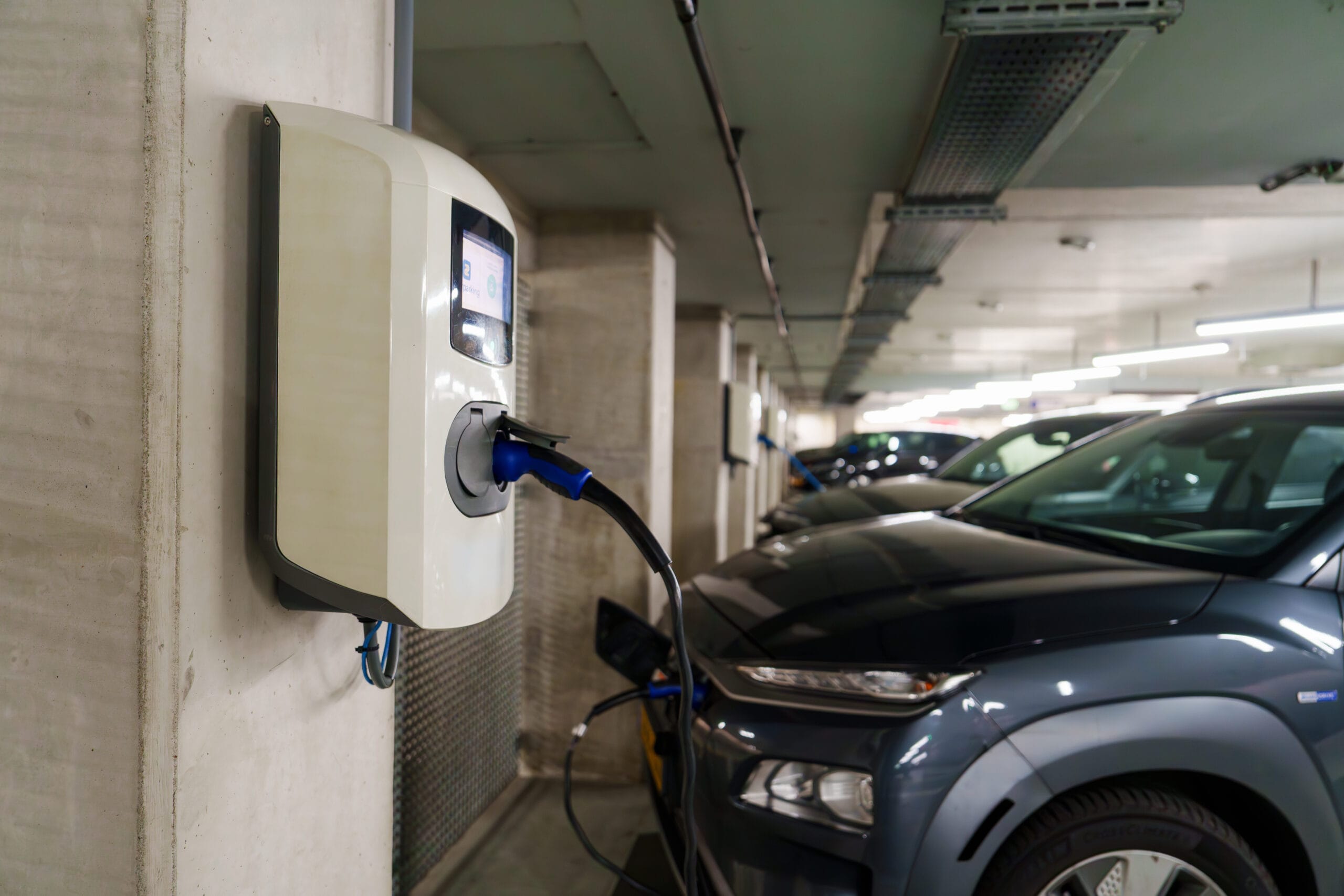 Recharging electric cars at the charging station in the underground parking. The concept of ecological energy systems. Electric cars in an underground car park at a charging station